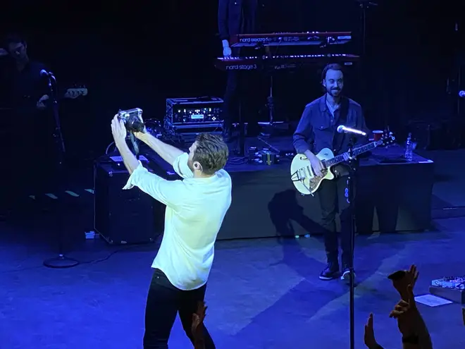 Brett Eldredge taking a photo of the audience in London on his Polaroid camera