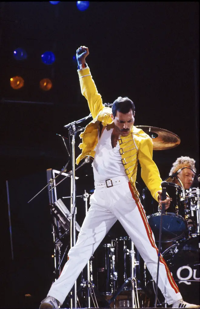 Freddie Mercury performs on stage with drummer Roger Taylor behind on the Magic Tour at Wembley Stadium, London, July 1986