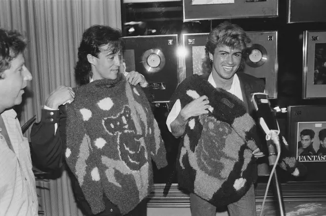 Andrew Ridgeley and George Michael holding koala motif sweaters during the pop duo's 1985 world tour, January 1985. Behind them are awards for record sales, including one for their first album, 'Fantastic'.