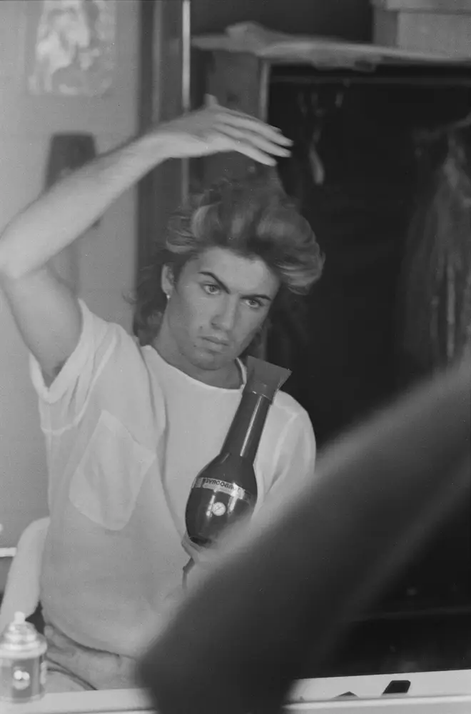 George Michael blow drying his hair during the pop duo's 1985 world tour, January 1985.