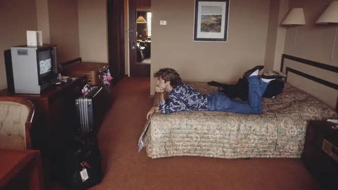 George Michael lies on a bed watching television in a hotel room in Sydney, Australia during the pop duo's 1985 world tour in January 1985.