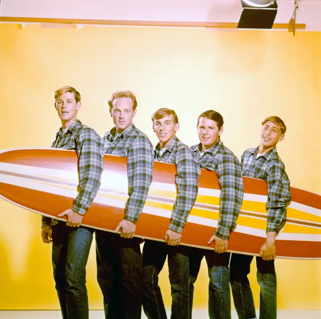 The Beach Boys pose for a portrait with a surfboard in August 1962 in Los Angeles, California