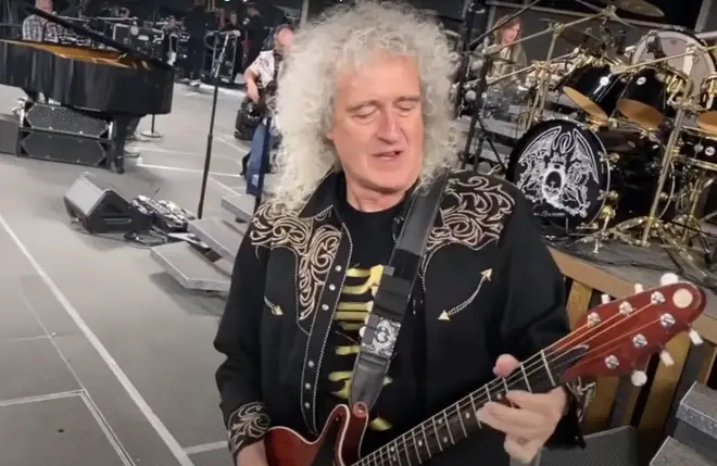 The footage shows Adam, Brian, Roger and their keyboardist Philip "Spike" Edney play a rousing rendition of &squot;Hammer To Fall&squot; to the vast arena as they dance and joke around with one another.