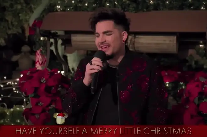 The Queen frontman was filmed sitting on a red brick wall, surrounded by festive red poinsettia flowers and fairy lights