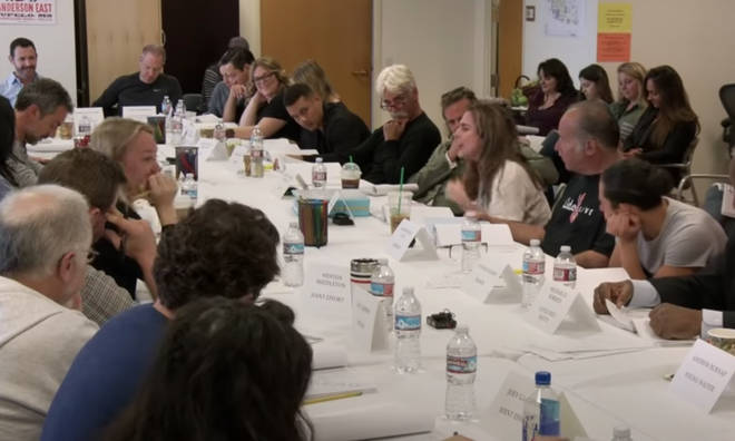 The video shows Lady Gaga and Bradley Cooper sitting side-by-side at a table and joined by crew, cast an executives for the movie A Star Is Born.