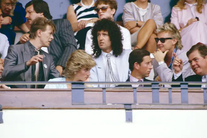 (Back: L to R) Davie Bowie, Brian May and Roger Taylor have a talk during the Live Aid Concert at Wembley Stadium as they sit behind sit behind Princess Diana and Prince Charles (front) on 13th July 1985.