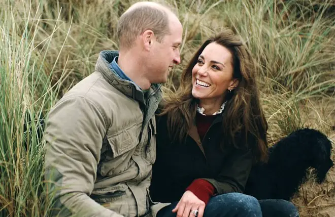 The footage shows the family on a walk on a Norfolk beach and Kate and William laughing and embracing as they sit in the sand dunes (pictured).