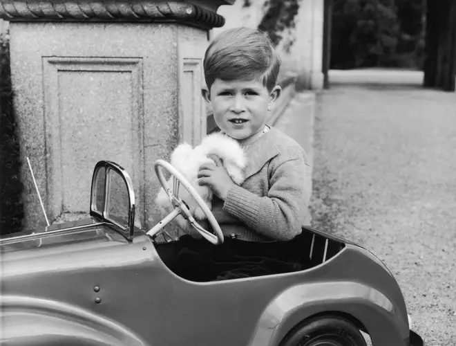 A fresh-faced Charles plays in a toy car in this black and white shot