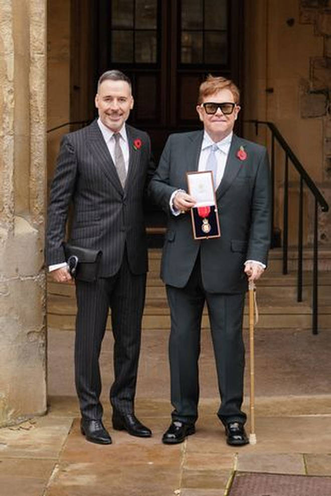 Elton's husband David Furnish held him closely whilst they posed for photographs outside Windsor Castle.