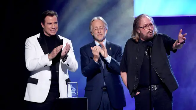 Barry Gibb accepts the Recording Academy President's Merit Award from actor John Travolta and Recording Academy President Neil Portnow onstage during 'Stayin' Alive: A GRAMMY Salute To The Music Of The Bee Gees' in 2017. (Photo by Kevin Winter/WireImage)