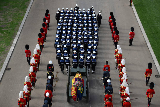 Royal Navy Sailors walk ahead and behind the coffin