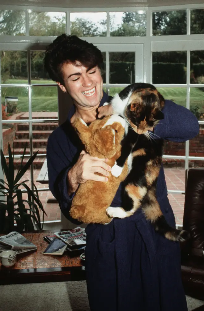 George Michael poses at home with his cat after losing his voice and being forced to cancel a number of live shows in 1980, London.