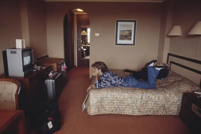 George Michael lies on a bed watching television in a hotel room in Sydney, Australia during the pop duo's 1985 world tour in January 1985.