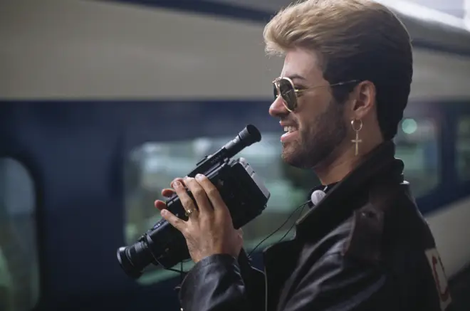 George Michael pictured holding a Sony video recorder device next to a bullet train on a station during the Japanese leg of his Faith World Tour in February 1988.