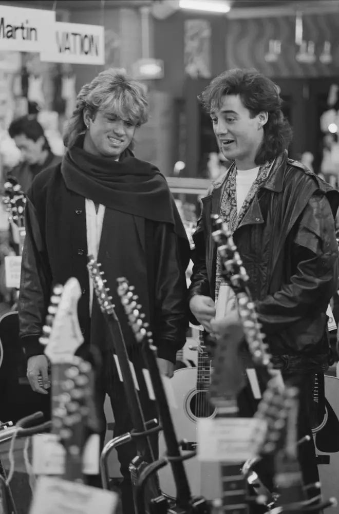 George Michael and Andrew Ridgeley of Wham! looking at a display of guitars for sale, during the pop duo's 1985 world tour, January 1985.