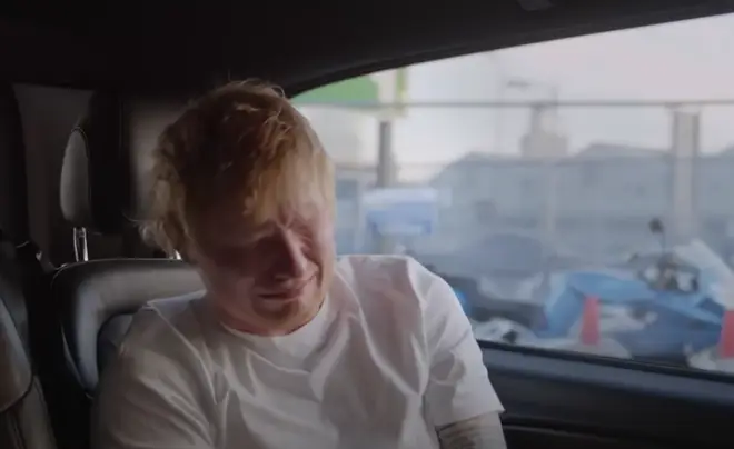 Sheeran can be seen sitting in the back of a car as he breaks down in tears, and later crying as he stands in front of a microphone.
