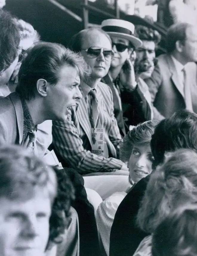 David Bowie talking to Princess Diana in the audience at Live Aid in 1985, with Elton John seated some distance away.