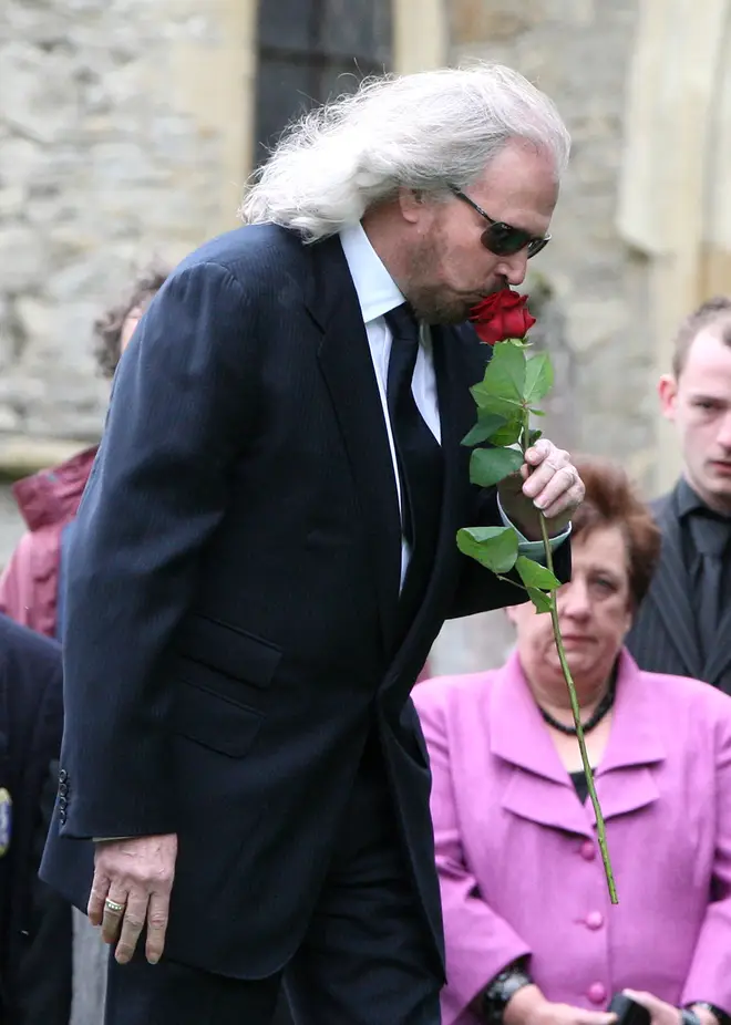 Barry Gibb kisses a rose just before placing it on the coffin at the funeral of brother Robin. (Photo by Danny Martindale/WireImage)