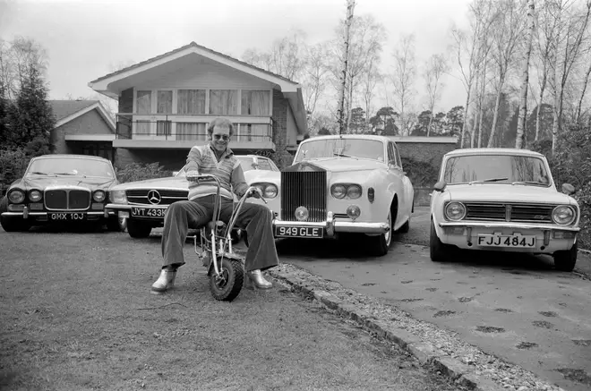 Elton John pictured at his home, sitting on a small motorbike in front of four of his cars. His cars include a Mercedes (2nd left) and a white Rolls Royce (3rd left) Picture taken 4th April 1972.