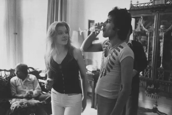 Freddie Mercury (R) drinking a class of champagne as his girlfriend Mary Austin looks on during party for friends at home in 1977