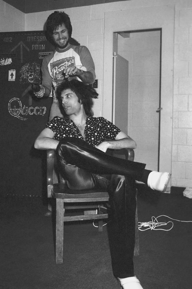 Freddie Mercury gets his hair done backstage by his hairdresser circa 1977.